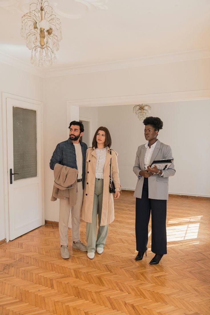 A professional property dealer showing a spacious new home to a couple. Partner with the top Real Estate Agency in Delhi NCR to find your perfect property investment.