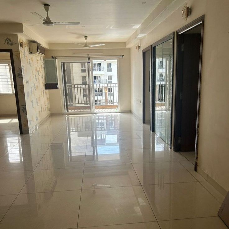 Interior view of a clean, modern empty apartment with shiny tile floors and a balcony. Find affordable houses and premium apartments for rent in Noida, Ghaziabad, and Hapur with our trusted Real Estate Services in Delhi NCR.